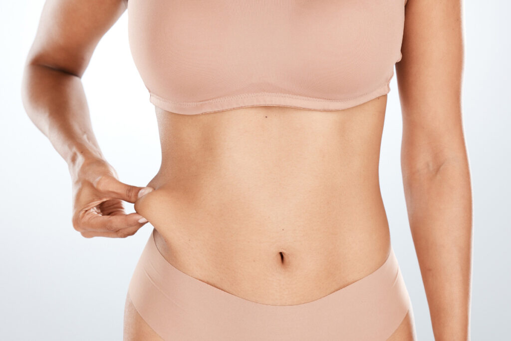 Individual pinching flank area to indicate targeted fat reduction by CoolSculpting.