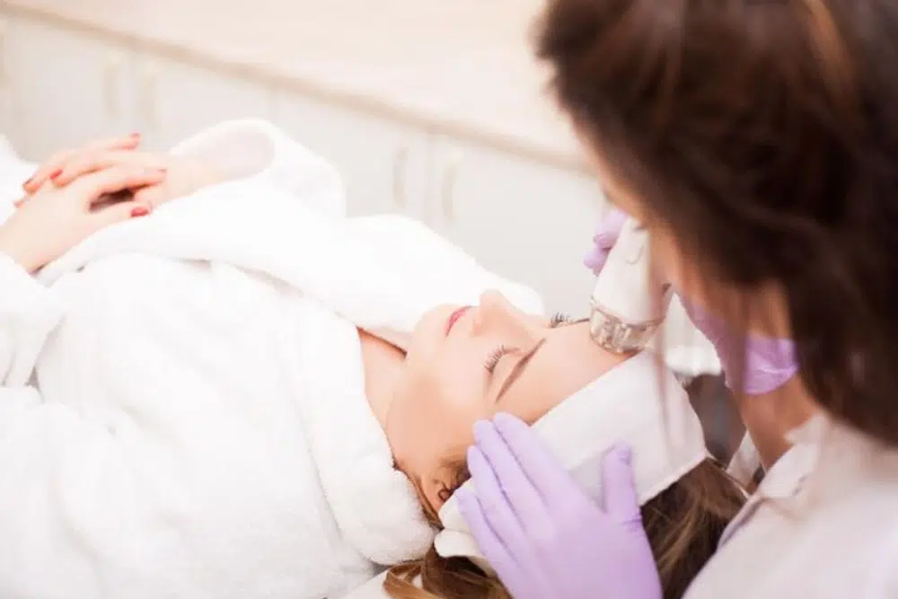 Woman with a plastic surgeon getting an Ultherapy treatment as a nonsurgical brow lift technique.