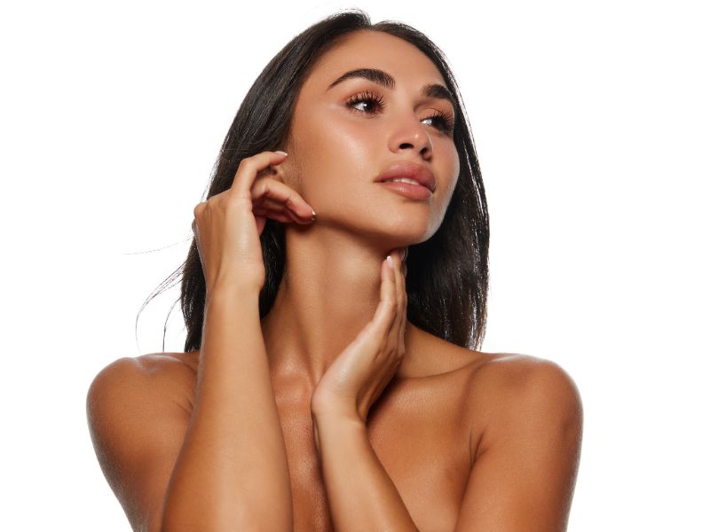 Woman with smooth, glowing skin touching her face, illustrating the rejuvenating effects of Fraxel laser treatments.